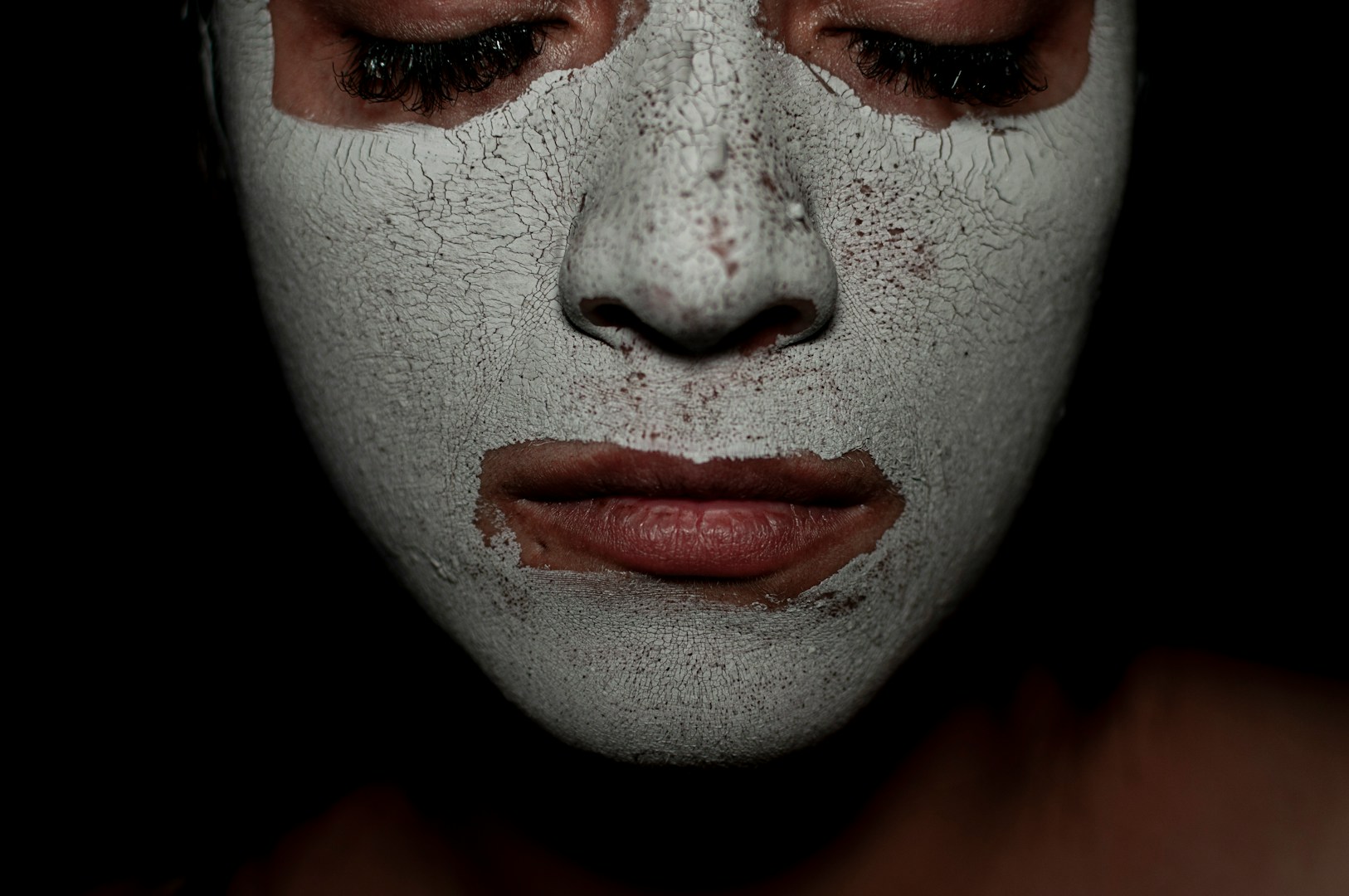 Person wearing a white face mask with closed eyes.